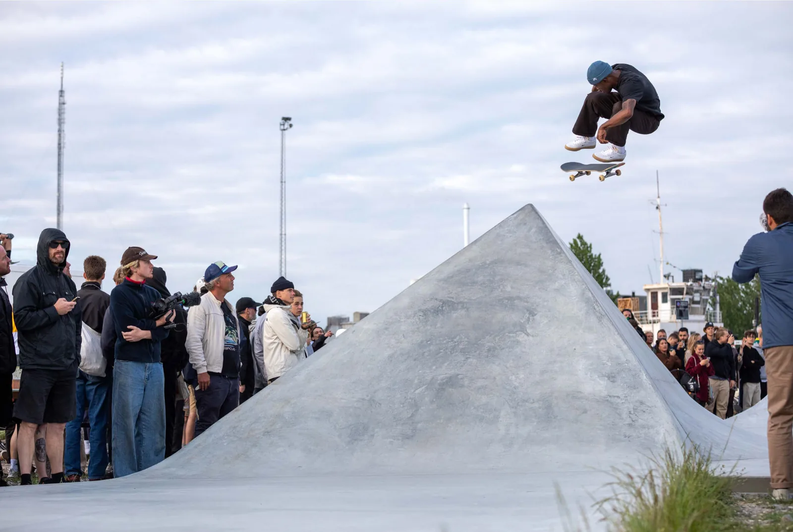 A skateboarder launches over a concrete ramp in front of a crowd