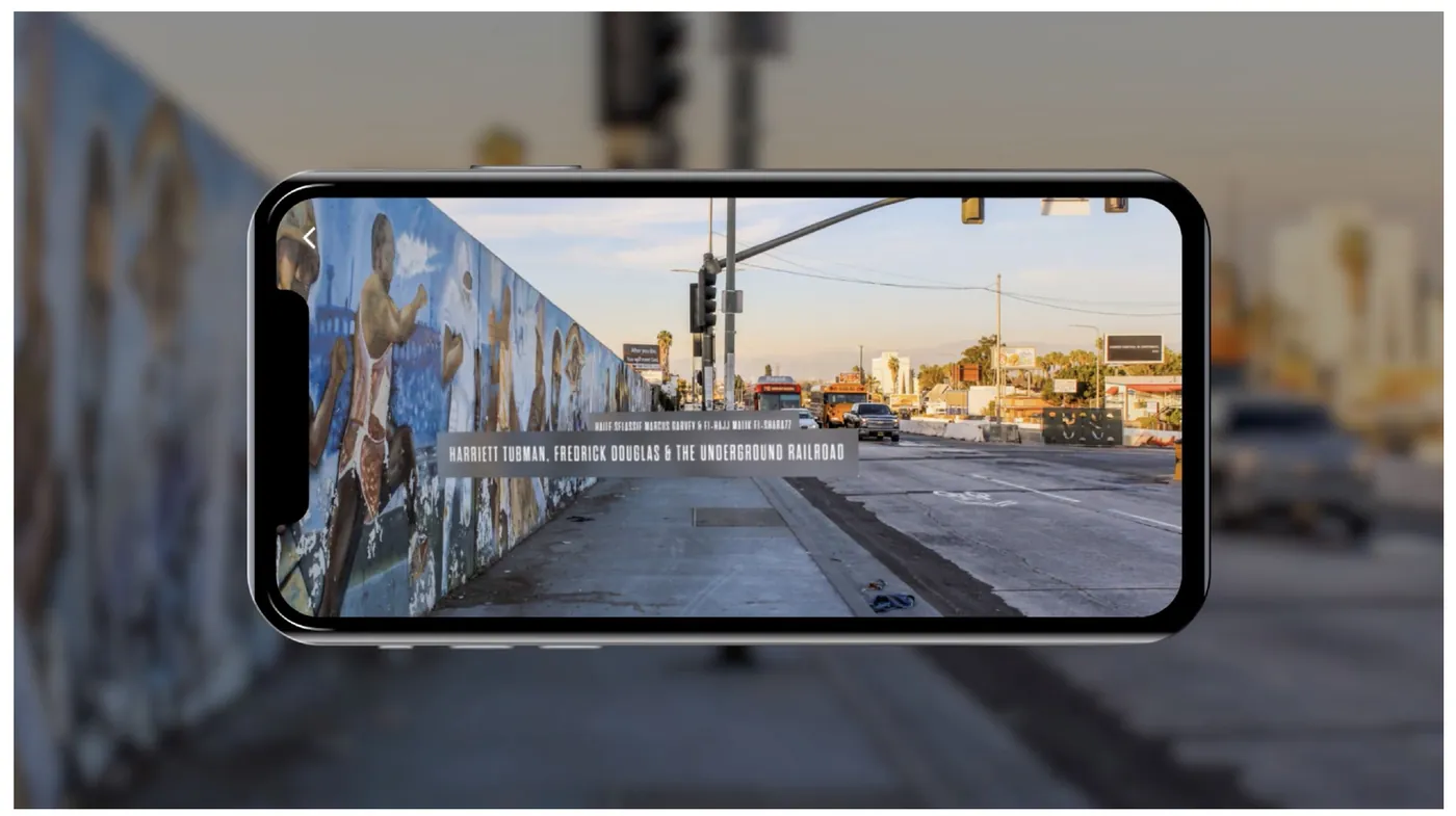 A phone held up to the Crenshaw Wall showing an AR overlay